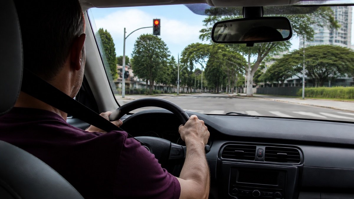 Motorista parado no sinal vermelho usando cinto de segurança